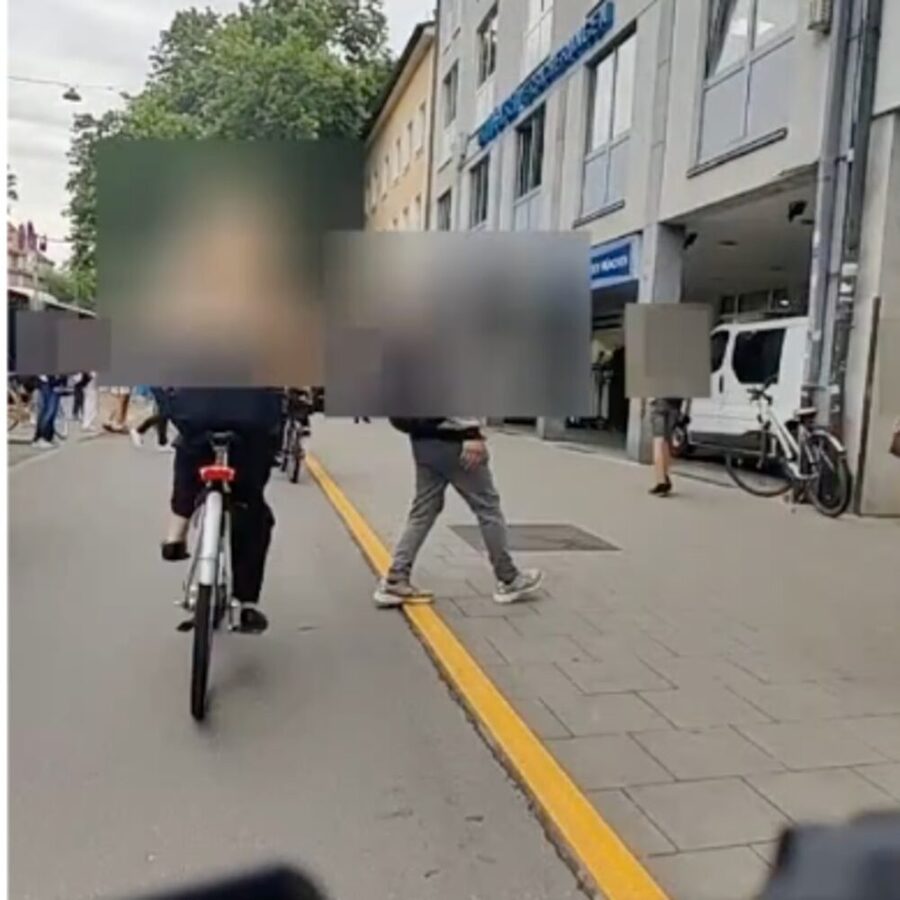 Rider's view: pedestrians walking on the sidewalk-level path in front of an approaching cyclist.